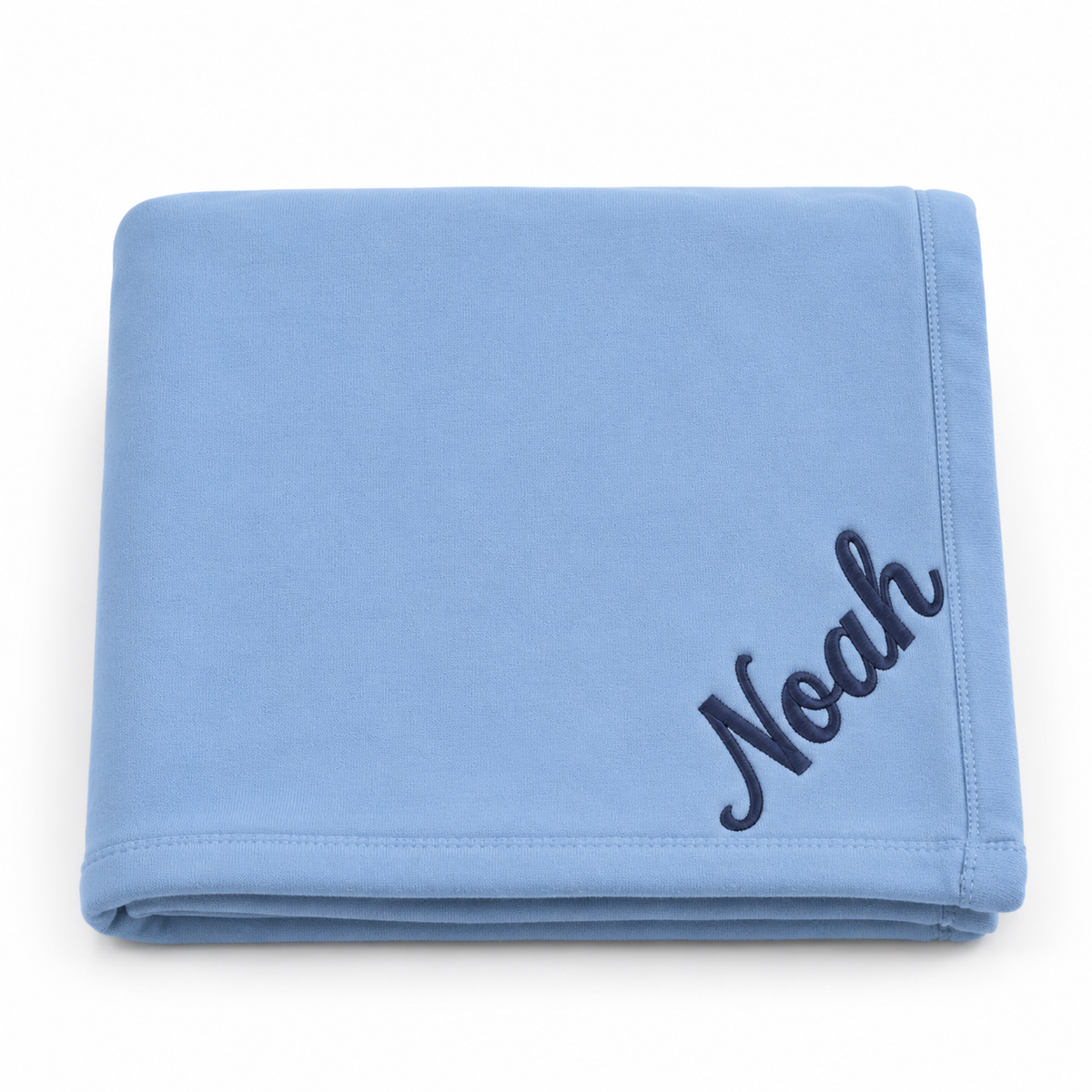 A folded light blue blanket with the name 'Noah' embroidered in dark navy script in the bottom right corner, set against a plain white background.