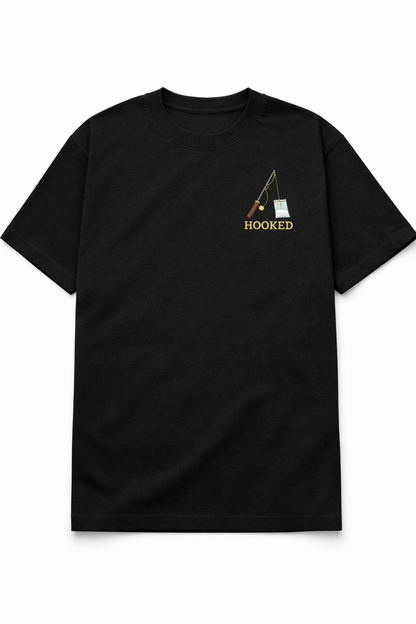 Black t-shirt featuring a small chest DTF print of a fishing rod with the word Hooked in a minimalist design