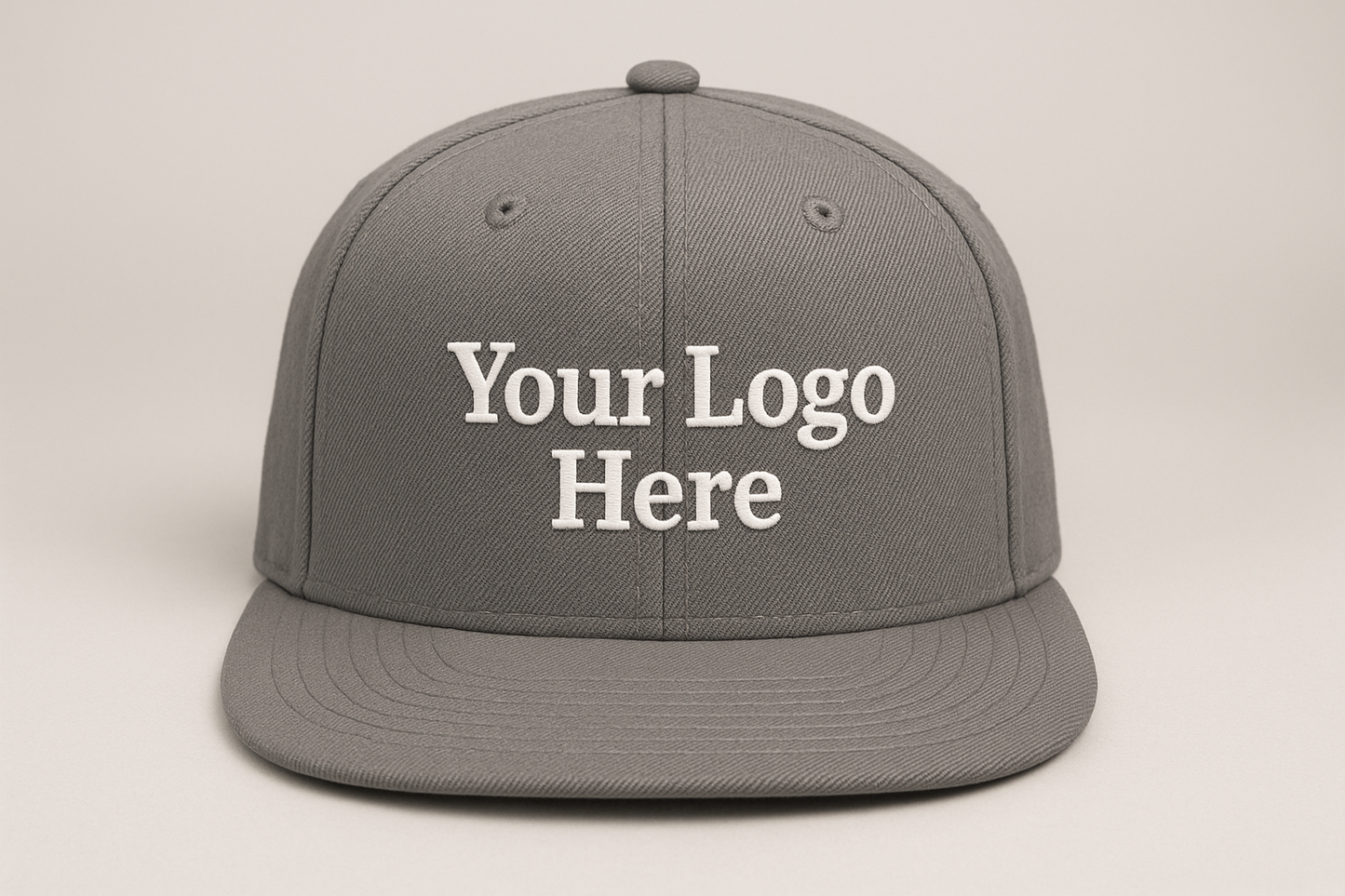 grey snapback flat brim cap, facing forward, with the text: "Your Logo Here" on the cap embroidered