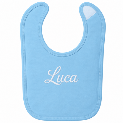 A light blue baby bib with the name 'Luca' embroidered in white script across the center, shown on a plain white background.

