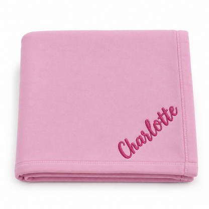 A folded pink blanket with the name 'Charlotte' embroidered in pink script on the corner, set against a plain white background.


