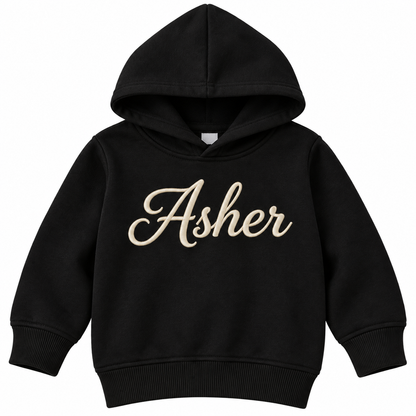 A black kids' pullover hoodie with the name 'Asher' printed across the chest in a beige cursive script, shown against a plain white background.

