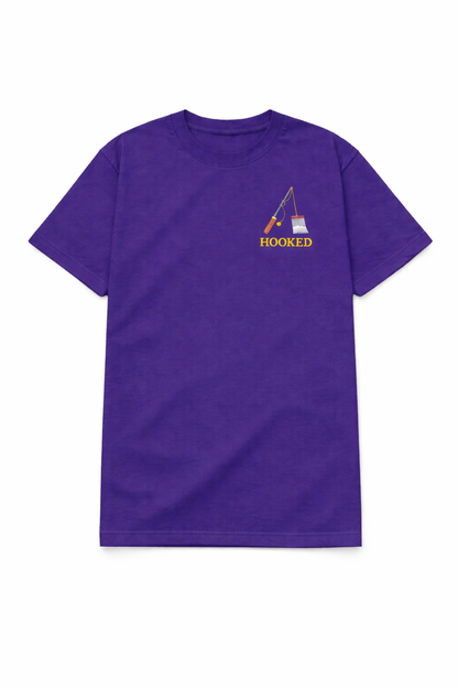Purple t shirt featuring a small chest DTF print of a fishing rod with the word Hooked in a clean design